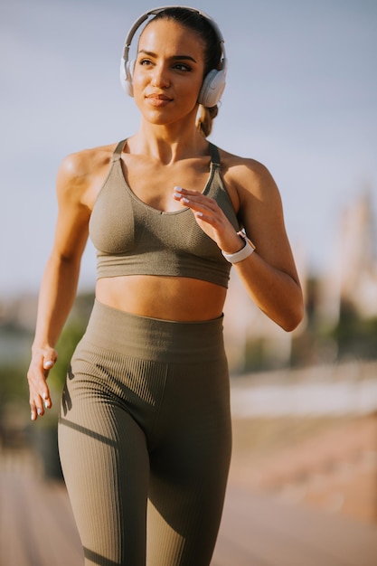 Active young beautiful woman running on the promenade along the riverside