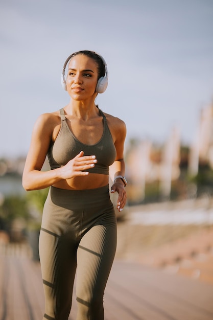 Active young beautiful woman running on the promenade along the riverside