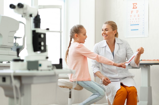 Active young girl pointing on elements of eye presented on a paper