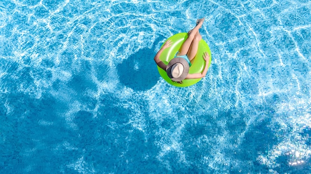 Active young girl in swimming pool aerial drone view from above teenager relaxes and swims on ring