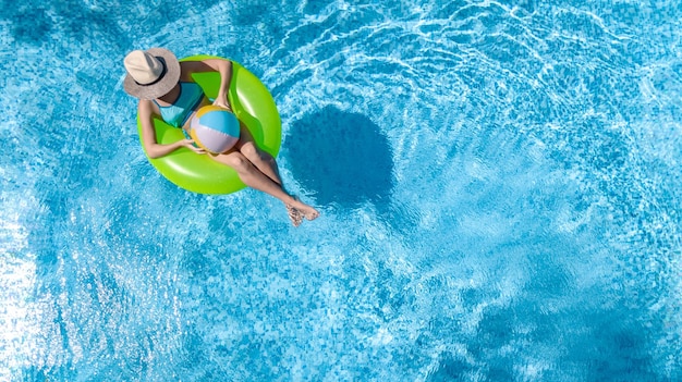 Active young girl in swimming pool aerial drone view from above teenager relaxes and swims on ring