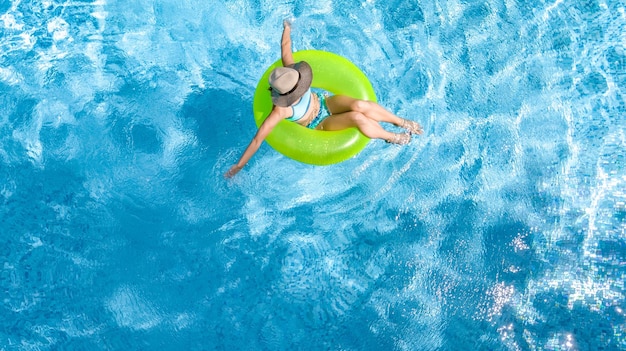 Active young girl in swimming pool aerial drone view from above teenager relaxes and swims on ring