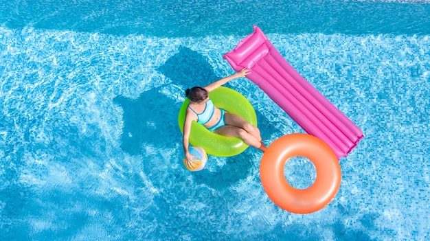 Active young girl in swimming pool aerial top view from above, teenager swims on inflatable ring