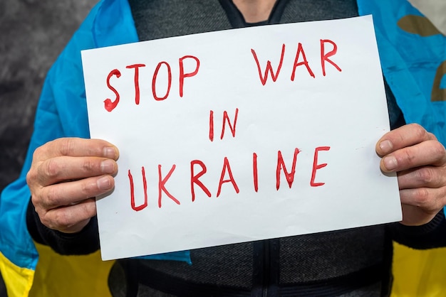 Photo activist holding poster with text no war in ukraine sign at a public demonstration peace for ukraine russia to the aggressor and the international theorist