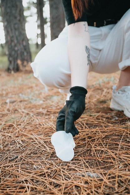 Activist young woman picking up trash with garbage tongs close upForest backgroundmountainGeneration zhappiness teaching and learning collecting garbage and recycleAwarenessrenewable sources