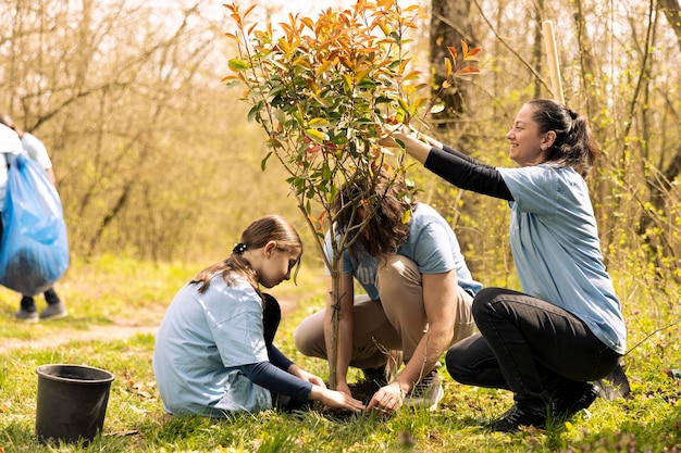 Photo activists and a girl installing a tree and covering hole in the woods