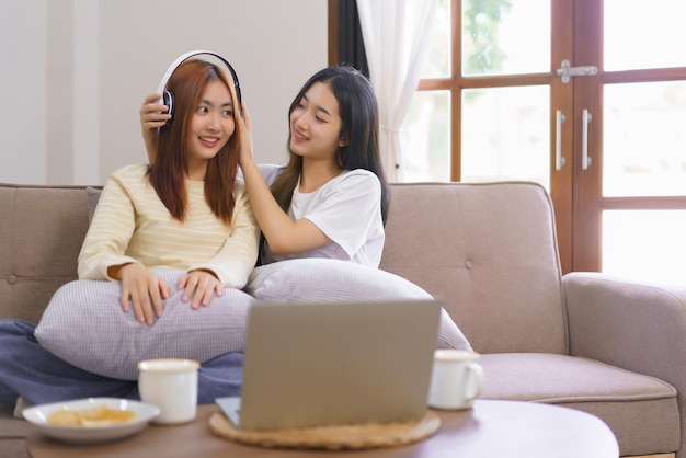 Activity at home concept Lesbian couple wears headphone to girlfriend and listening music together