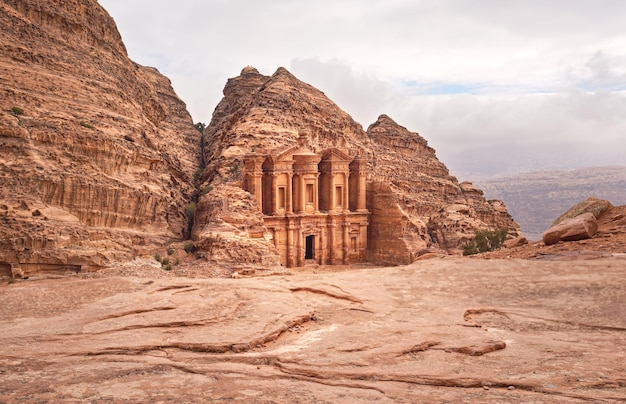 Ad Deir - Monastery - ruins carved in rocky wall at Petra Jordan, mountainous terrain with overcast sky background