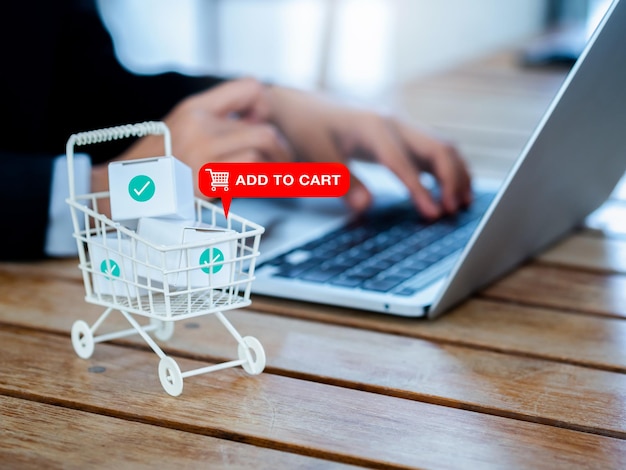 Add to cart icon sign appear on white shopping trolley cart contained parcel boxes with check marks near the business person who using laptop computer online shopping client customer concept