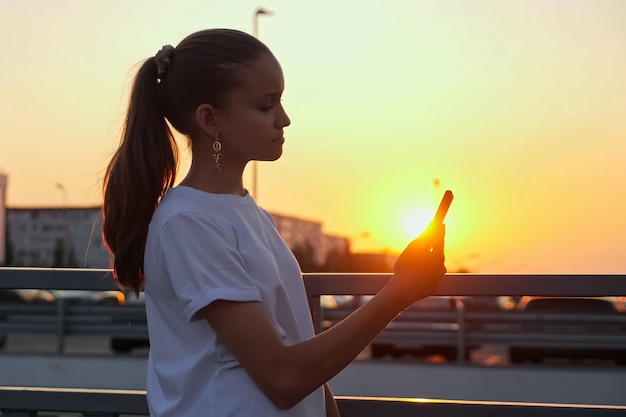 Addicted young teenage girl with ponytail holds smartphone