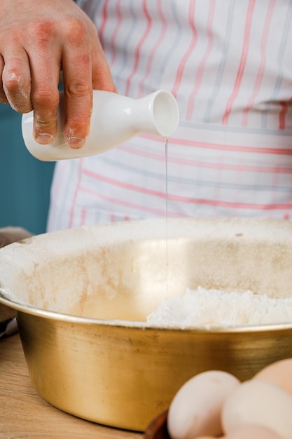 Adding butter to the raw dough close-up. The baker prepares pastries for bread with all the ingredients.