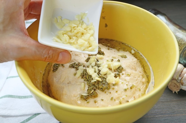 Adding chopped fresh garlic onto kneaded dough for baking Italian Focaccia bread