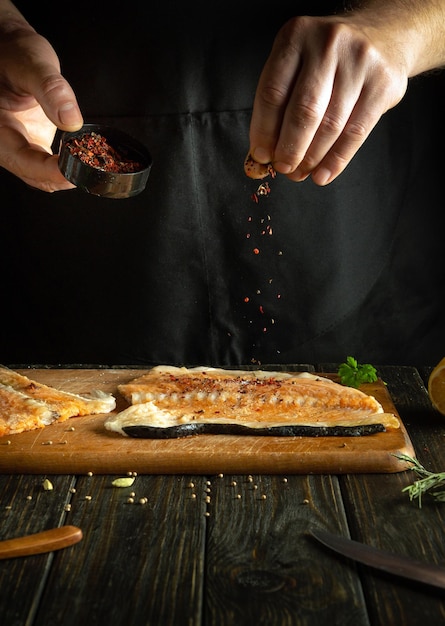 Adding dry spices to fish steaks for aroma and taste American cuisine The process of preparing fish by the hands of a chef in a restaurant or hotel kitchen