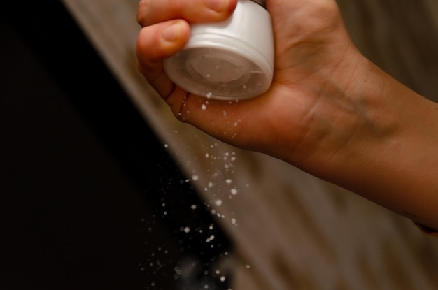 Adding salt. Backlight to salt from salt shaker. Close up