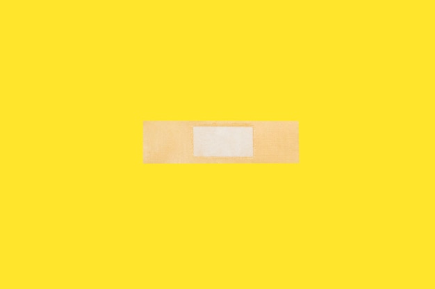 An adhesive bandage on a yellow background with copy space