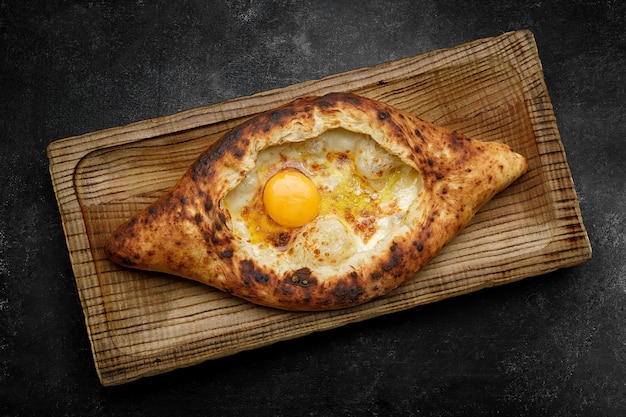 Adjarian khachapuri with egg on a wooden board