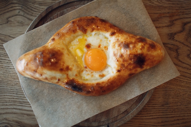 Adjarian khachapuri with suluguni cheese and egg and butter. Top view.