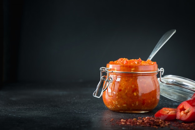 Adjika hot chili pepper sauce paste harissa in glass jar. Tunisia, georgian and arabic cuisine. Horizontal. 