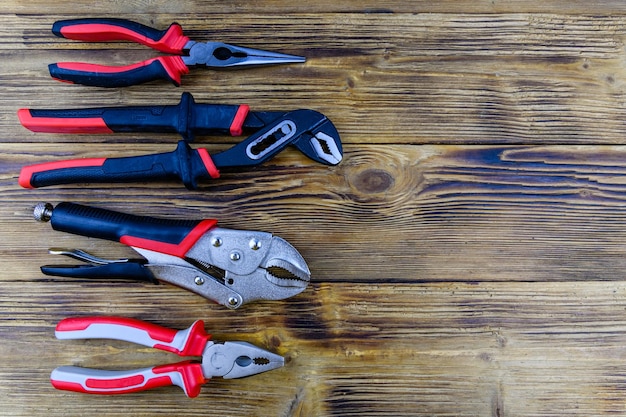 Adjustable water pump pliers needle nose pliers and locking pliers on a wooden background Top view