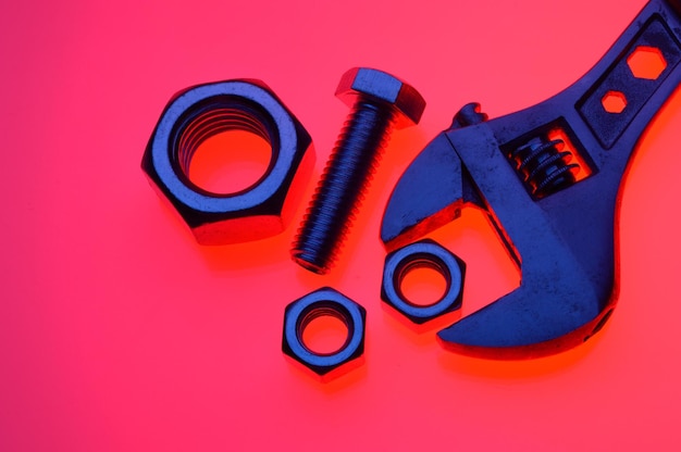 Adjustable wrench and nuts of different sizes on a red backgroundCloseup