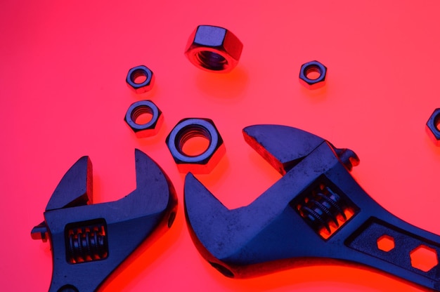 Photo adjustable wrench and nuts of different sizes on a red backgroundcloseup