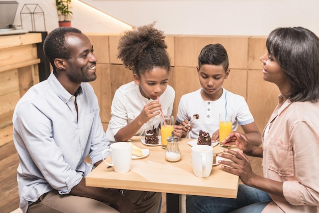 adorable african-american family eating desserts in cafe