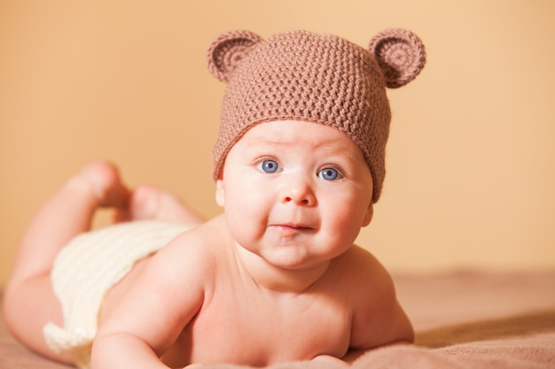 Adorable baby in bear hat lying on the bed