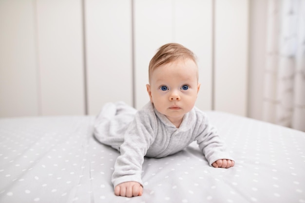 Adorable baby boy in white sunny bedroom Newborn child relaxing on a bed