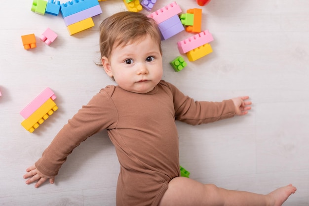 Adorable baby in brown shirt playing with toys card banner space for text high quality photo