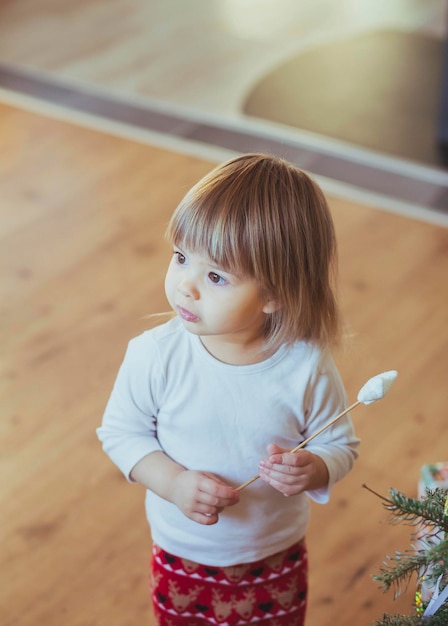 Adorable baby playing with magic wand near christmas tree