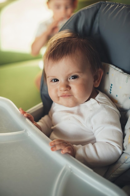 Adorable baby sitting in a highchair and looking suspiciously at the camera facial expressions baby