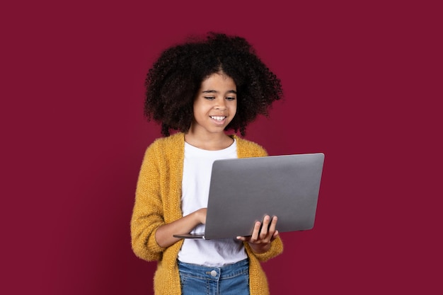 Adorable black girl schooler using modern computer