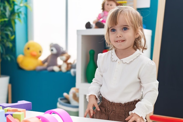 Adorable blonde girl smiling confident standing at kindergarten