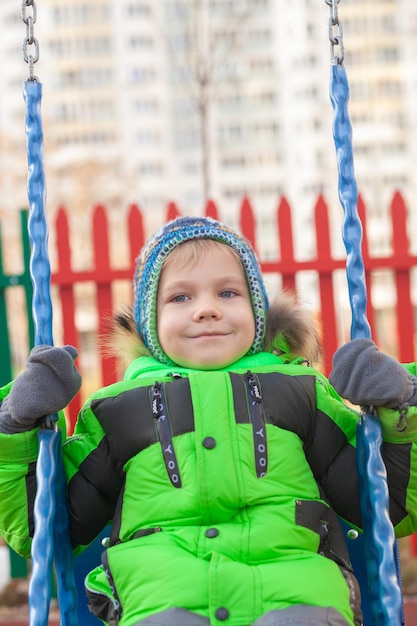 Adorable boy having fun on a swing on autumn day