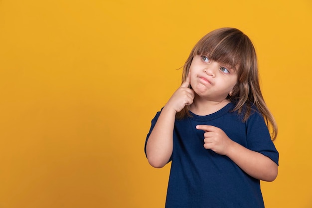 Adorable caucasian girl thinking on yellow background with free space for text