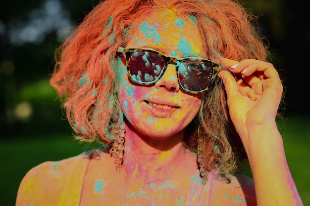 Adorable caucasian model wearing glasses covered by dry Holi paint