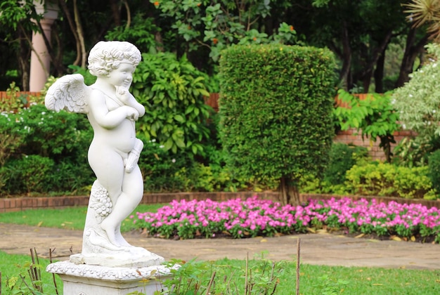 Adorable cupid sculpture in the flowering garden