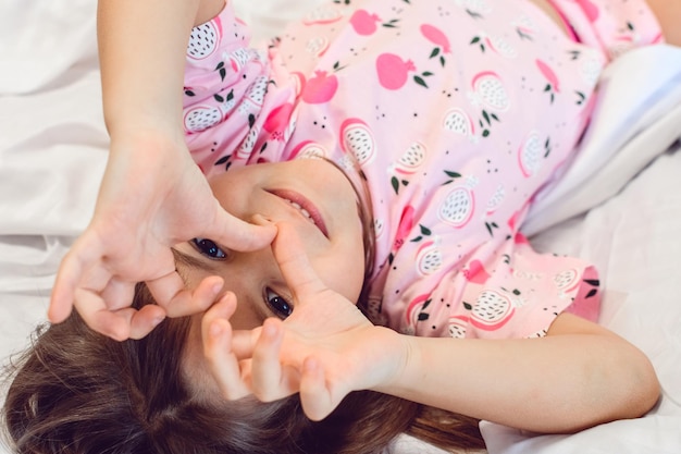 Adorable dark hair girl sleeping sweetly in the morning on wihte bed linens at home Childrens dreams comfort rest and peace