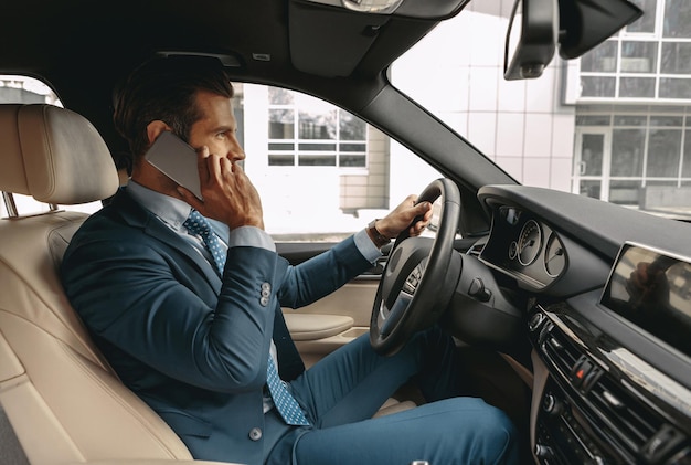 Adorable elegant man in suit driving an automobile