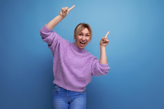 Adorable energetic pleasant blond young woman with a grimace on a bright plain background