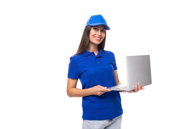 Adorable european young brunette woman promoter in blue tshirt and cap holding laptop