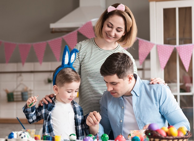 Photo adorable family with child painting eggs