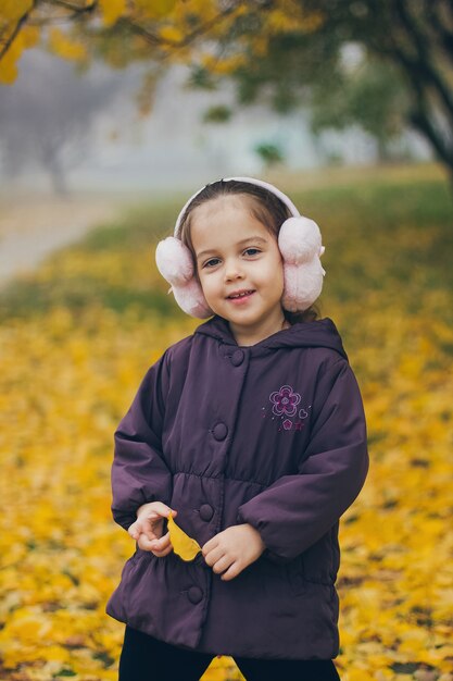 Adorable funny little girl in the park on beautiful autumn day.