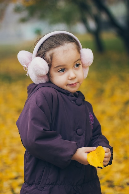 Adorable funny little girl in the park on beautiful autumn day.