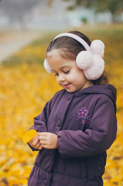 Adorable funny little girl in the park on beautiful autumn day.