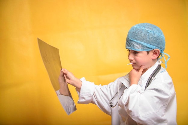 Adorable future doctor 7 years old boy isolated on yellow