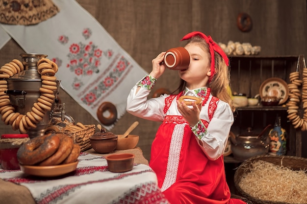 Adorable girl drinking tea from samovar