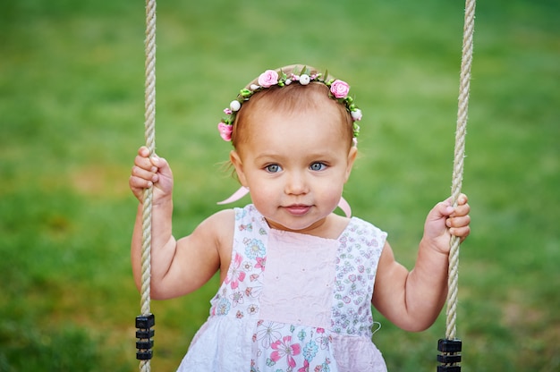 Adorable girl having fun on a swing on summer day