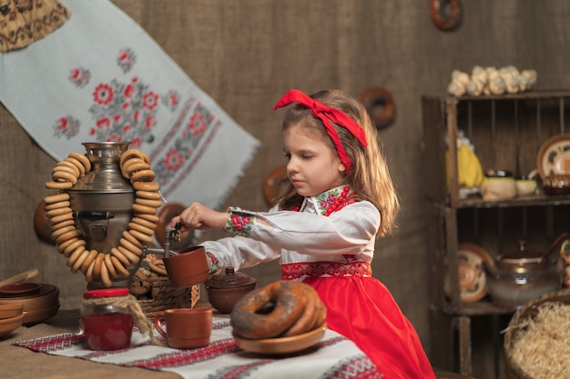 Adorable girl pouring tea from samovar