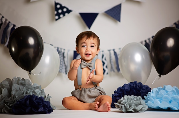 Adorable happy baby boy in a bright room decorated with balloons